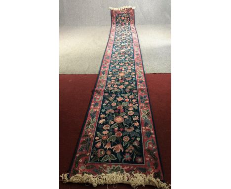 Runner, hand woven with Arts and Crafts floral motifs on a midnight field within complementary borders. L.535 W.79cm. 
