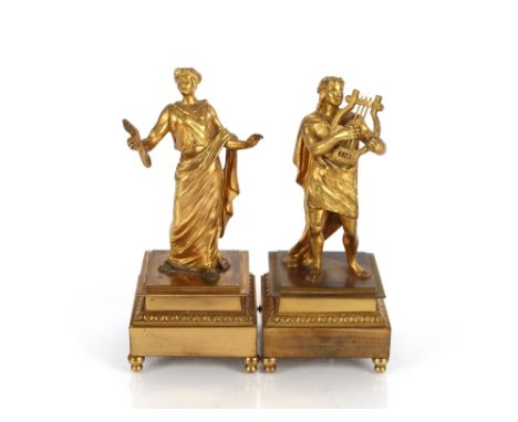 A pair of Ormolu figures depicting musicians, raised on square stepped leaf bordered bases terminating in ball feet, the larg