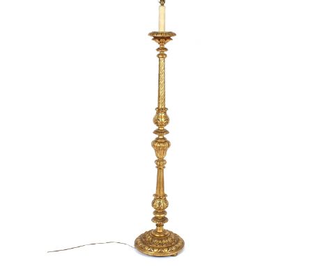 A large gilt standard lamp, having foliate and reeded decoration to the baluster column, red tasselled shade, 190cm high over