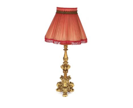 A Florentine style gilt table lamp, having raised foliate decoration and scrolled feet, complete with red pleated shade, 120c