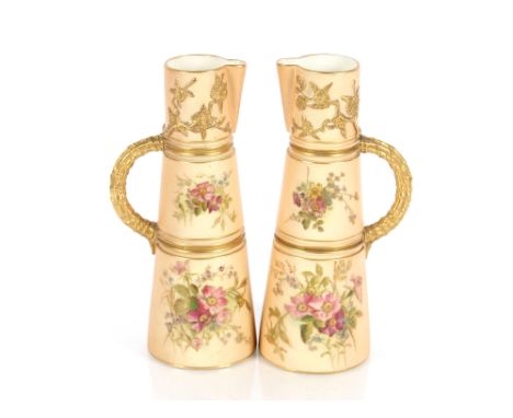 A pair of Royal Worcester jugs, of tapering form, having foliate spray decoration on blush ivory ground heightened in gilt, c