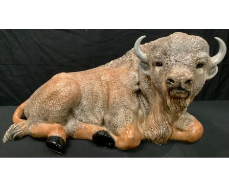 A large Italian ceramic model of a resting bison, naturalistically modelled and glazed in shades of brown, 60cm wide, 31cm hi
