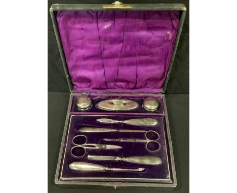 An early 20th century nine piece manicure set, comprising scissors, silver hafted tools, silver buffer and silver topped jars