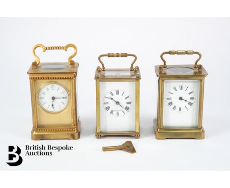 Three brass carriage clocks, two of them with white enamel faces with Roman dial complete with keys together with a gilt bras