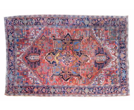 AN OLD HEREZ CARPET with polychrome polygonal panels within a deep blue border, 338 x 235cm
