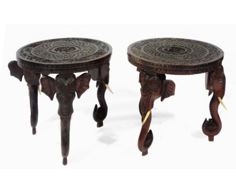 A PAIR OF INDIAN CARVED WOOD CIRCULAR OCCASIONAL TABLES each on three elephant trunk supports, 45cm diameter