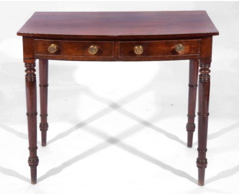 A LATE GEORGIAN MAHOGANY BOW FRONT SIDE TABLE with two drawers with brass handles on ring turned legs, 81cm wide