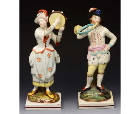 A PAIR OF ENGLISH PEARL WARE FIGURES of a boy playing a French horn and girl with tambourine with polychrome decoration on na