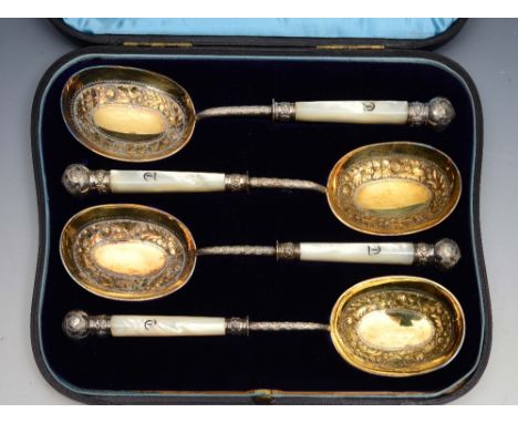 A SET OF FOUR LATE VICTORIAN GILDED PLATE SERVING SPOONS with mother of pearl handles and embossed decoration in presentation