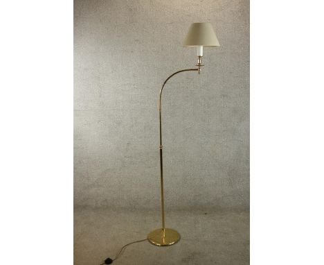 A contemporary brass floor standing lamp with adustable arm raised on circular foot. H.184cm. 