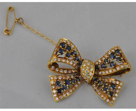 An 18ct. gold,&nbsp;sapphire and diamond brooch, in the form of a tied bow, each section of "ribbon" set round cut sapphires 