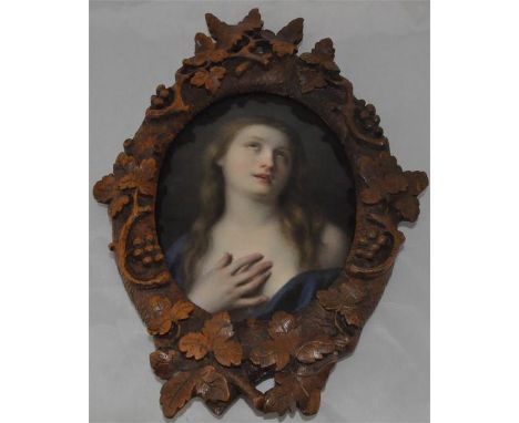 An oval KPM porcelain painted portrait of a maiden, contained with a Black Forest carved leaf and branch frame, plaque 17 cm 