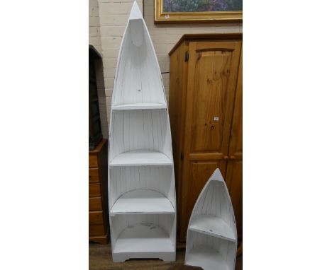 A tall white painted boat shaped reclaimed bookcase or display shelf 