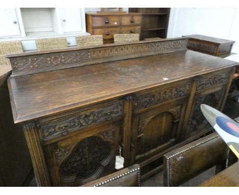 A 1920's/30's heavy oak dining room suite, comprising refectory style drawer leaf table on carved bulbous legs and carved cro