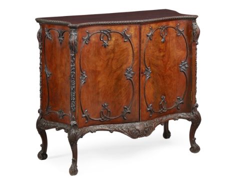 CHIPPENDALE STYLE MAHOGANY COMMODE  EARLY 20TH CENTURY   the serpentine top with a carved edge, above a pair of doors with fo