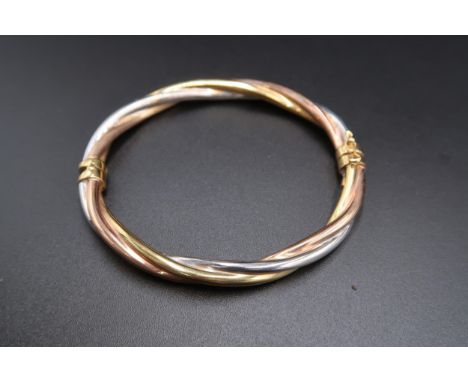 A 9ct tri colour gold twist hinged bangle. Weight 9.47 grams