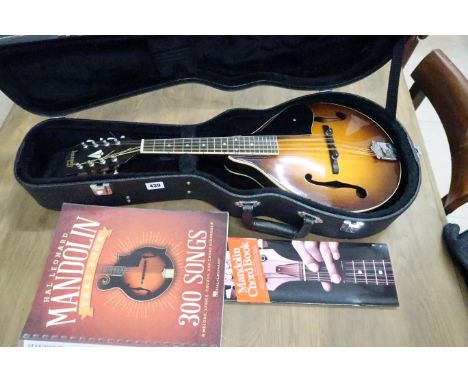 A mandolin with curved back and later added Gibson logo label, cased and a number of mandolin books.