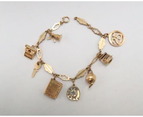 A 9ct gold leaf link charm bracelet with eight charms including a telephone with moving dial, windmill and typewriter, total 