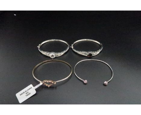 A group of four silver bangles, set with quartz, topaz, zircon, ruby and diamond. Weight 40.41 grams.