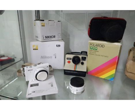 A Nikon J4 model camera and case and vintage polaroid camera and Nikkor 10mm f2.8 lens