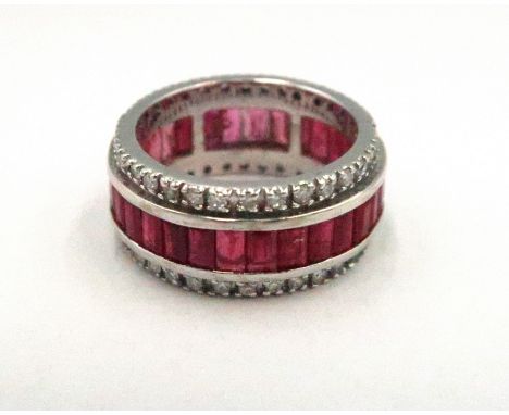 An 18ct white gold, ruby and diamond eternity ring, set with thirty baguette cut rubies, bordered by diamond brilliants, size
