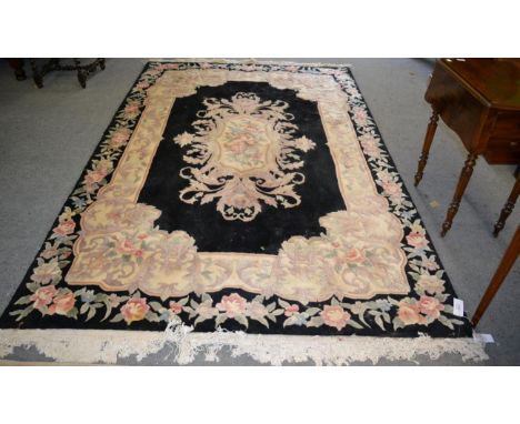 A Savonerie design carpet, the jet black field centred by a floral oval medallion framed by spandrels and floral borders, 367