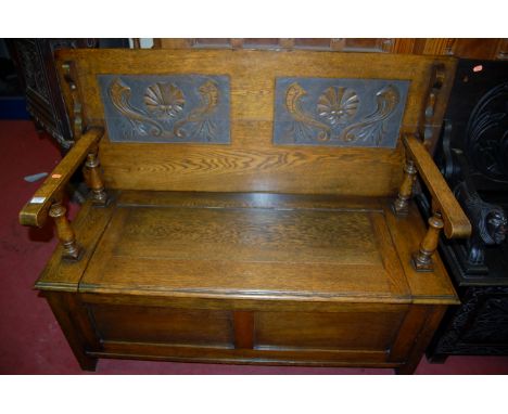 An early 20th century relief carved oak two seater fold-over monks bench, width 122cm
