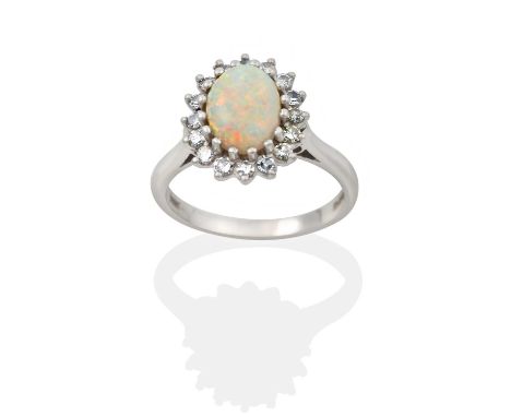 the oval cabochon opal within a border of eight-cut diamonds, in white claw settings, to a tapered shoulder plain polished sh