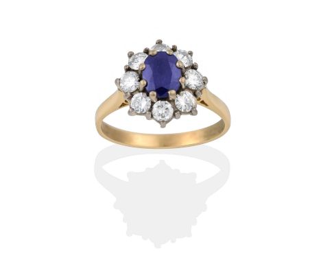 the oval cut sapphire within a border of round brilliant cut diamonds, in white claw settings, to a yellow tapered shoulder p