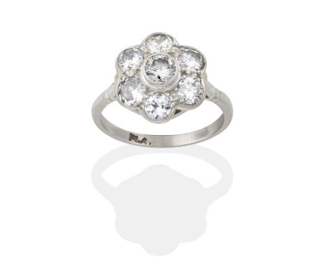 the round brilliant cut diamond within a border of smaller round brilliant cut diamonds, in white rubbed over settings, to a 