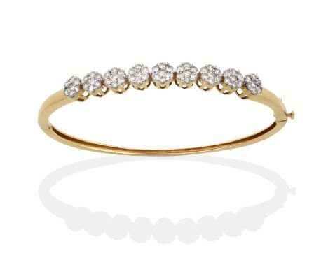 nine clusters set throughout with round brilliant cut diamonds, in white claw settings, to a yellow plain polished back, tota
