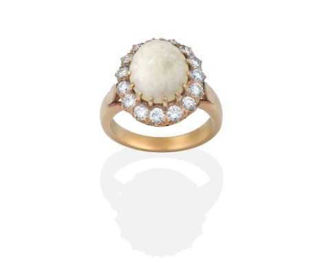 the oval cabochon opal within a border of round brilliant cut diamonds, in yellow claw settings, to a tapered shoulder plain 