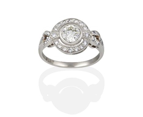 the central round brilliant cut diamond in a white rubbed over setting, within a spaced border of round brilliant cut diamond