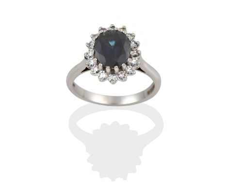 the oval cut sapphire within a border of eight-cut diamonds, in claw settings, to a tapered shoulder plain polished shank, to