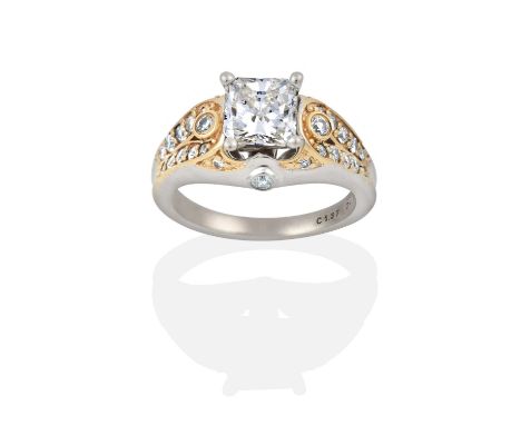 the princess cut diamond in a white four claw setting, to round brilliant cut diamond set fancy shoulders in yellow claw sett