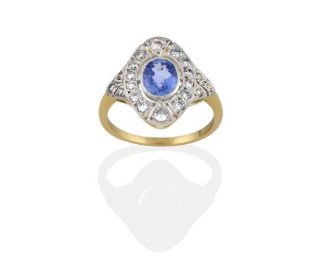 the oval cut sapphire within a round brilliant cut diamond set pierced plaque border, to similarly set shoulders, in white mi