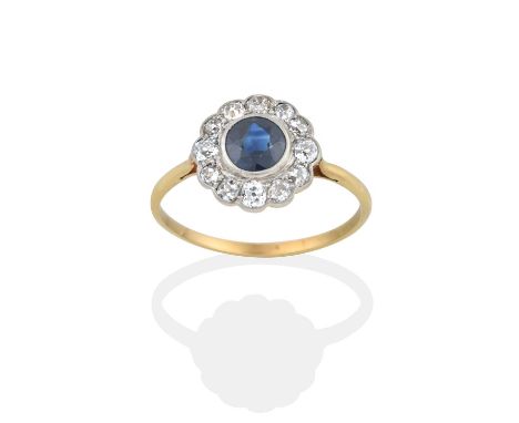 the round cut sapphire within a border of old cut diamonds, in white rubbed over and claw settings, to a yellow tapered shoul