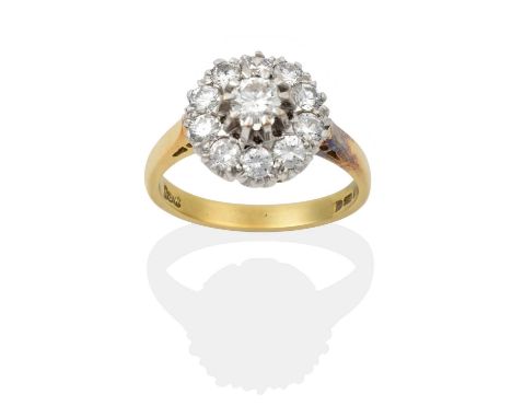the central raised round brilliant cut diamond within a border of smaller round brilliant cut diamonds, in white claw setting