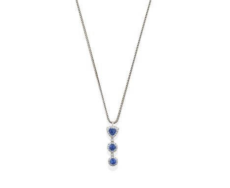 a trilliant shaped sapphire within a border of round brilliant cut diamonds suspends two graduated round cut sapphires in rou