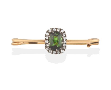the cushion shaped green tourmaline within a border of old cut diamonds, in white claw settings, to a yellow plain pin, total