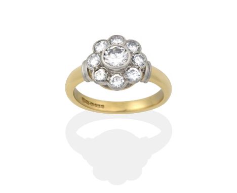 the round brilliant cut diamond within a border of smaller round brilliant cut diamonds, in white rubbed over settings, to a 