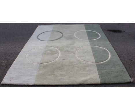 A modern thick pile rug decorated with three cream circles and a green circle against three light-green sections (227 x 172 c