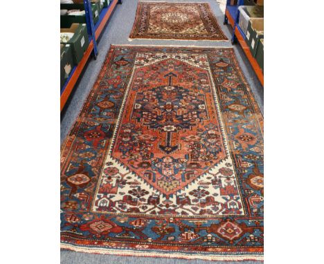 Two similar rugs: 1. a North West Persian hand-knotted rug with central cobalt-blue medallion against a rose-coloured lozenge