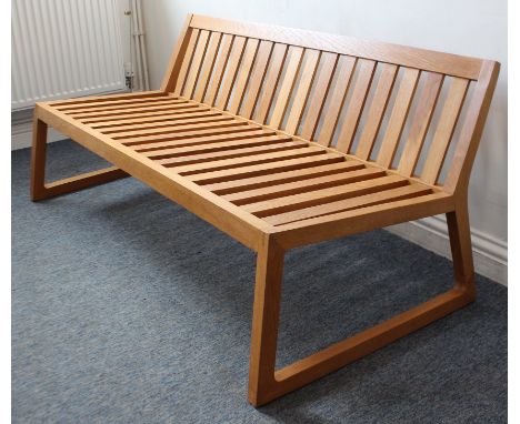 A Scandinavian-style light natural oak chair-back settle: short angular back with vertical splats; two shaped slightly angled