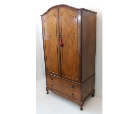 An early 20th century figured walnut veneered dome-topped cabinet on chest; the two panelled doors opening to reveal a top sh