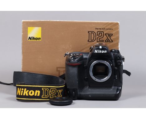 A Nikon D2x DSLR Camera Body, serial no 5014157, body G, light wear, with body cap, strap, manual, battery, MH-21 charger, in