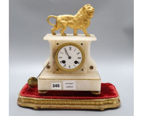 A 19th century French eight day alabaster mantel clock, surmounted by a gilt metal model of a lion, under a glass dome, heigh