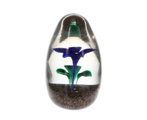 Strathearn ovoid glass paperweight, modelled with a blue flower planted in a soil base, marked with an S cane, 3.75" high