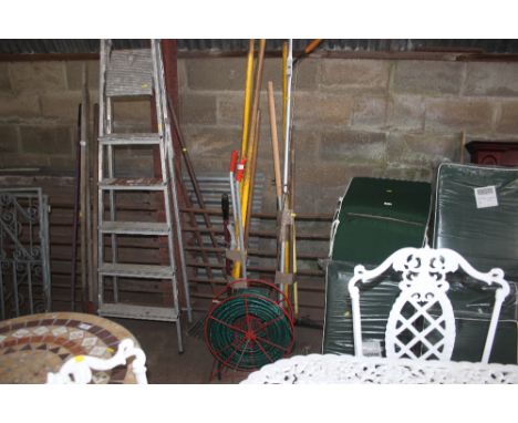 Two bundles of gardening tools and a hose and reel