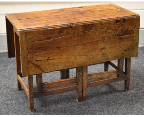 A nineteenth century joined oak gate leg table, the base with twin 'gates' at either side extending to 121cms long, 104cms wi